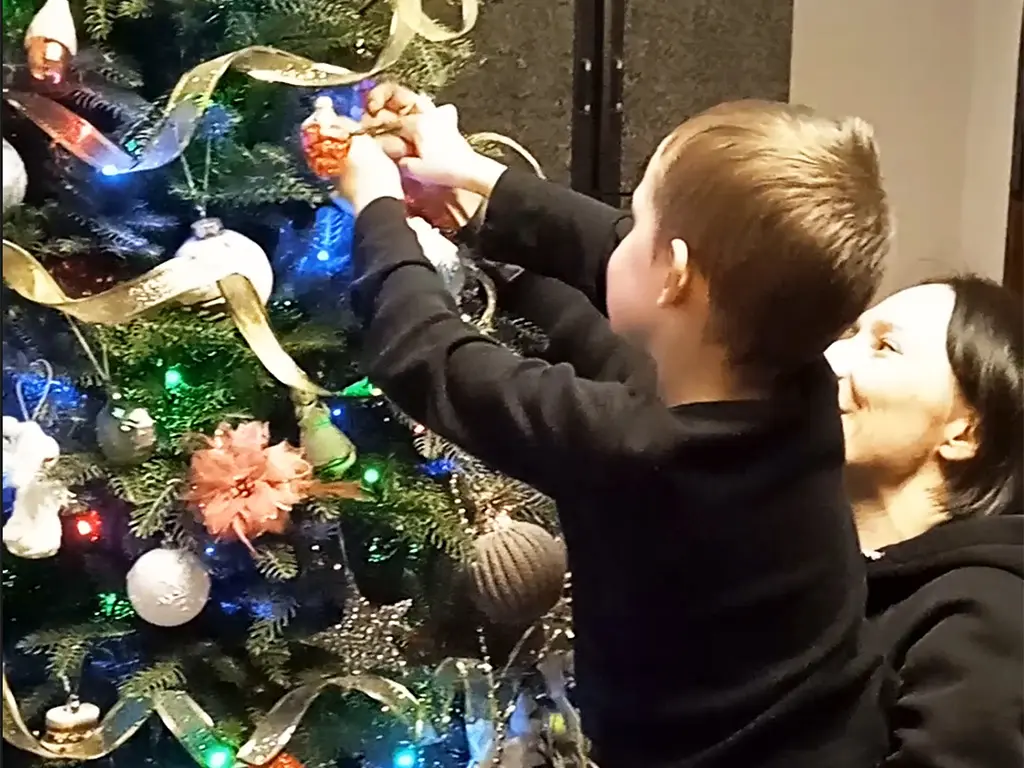 Mom helps Timosha to hang a new cristmas tree decoration